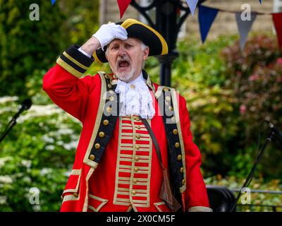 Crier de la ville masculine (livrée de crieur tressé rouge coloré) proclamant une annonce et faisant une proclamation publique bruyante - Ilkley, West Yorkshire Angleterre Royaume-Uni. Banque D'Images