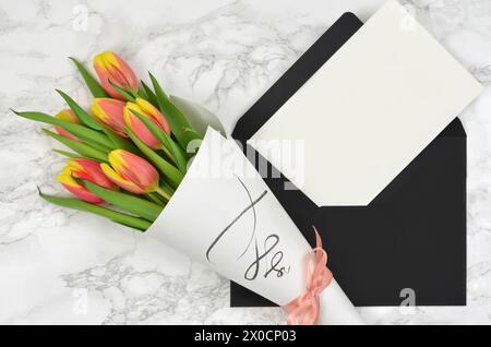 Bouquet de tulipes et feuille blanche de papier avec beaucoup d'espace pour remplir avec le contenu, enveloppe noire. Vue de dessus. Banque D'Images