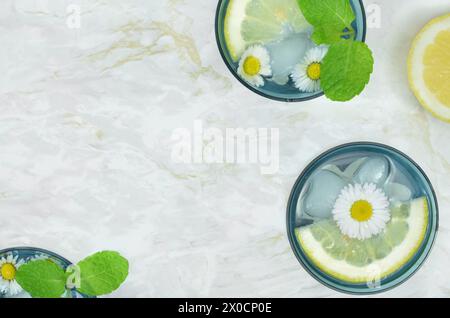 Verres bleus avec des boissons décorées avec de la menthe, du citron et des fleurs et un espace vide pour remplir avec du contenu. Banque D'Images