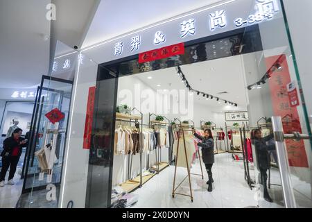 (240411) -- HANGZHOU, 11 avril 2024 (Xinhua) -- Un propriétaire de magasin organise des vêtements de tricot sur un marché de tricot dans la ville de Puyuan, dans la province du Zhejiang, dans l'est de la Chine, 9 avril 2024. Puyuan, le plus grand centre de tricot en Chine, a vu son volume d'affaires de tricot dépasser 130 milliards de yuans (environ 17,96 milliards de dollars américains) en 2023. Ces dernières années, Puyuan a intensifié ses efforts pour se développer en un cluster industriel avancé de tricots dans le delta du fleuve Yangtsé. (Xinhua/Xu Yu) Banque D'Images