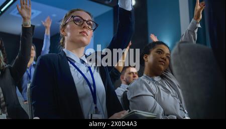 Les travailleurs de la presse multiethniques lèvent la main assise dans le bâtiment du gouvernement. Journaliste féminine pose des questions et écoute la réponse du représentant de l'organisation ou de l'homme politique pendant la conférence de presse. Banque D'Images
