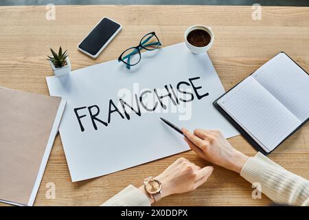 Une femme d'affaires assise à une table avec un panneau qui dit franchise dans un cadre de bureau moderne. Banque D'Images