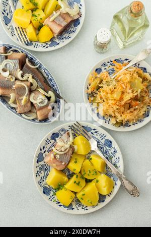 Délicieux dîners de poisson copieux, pommes de terre bouillies avec hareng mariné, choucroute avec oignons et huile d'olive, vue de dessus Banque D'Images