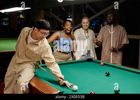 Portrait d'homme asiatique souriant jouant au billard et faisant le tour de tir avec divers groupes d'amis encourageant l'espace de copie Banque D'Images