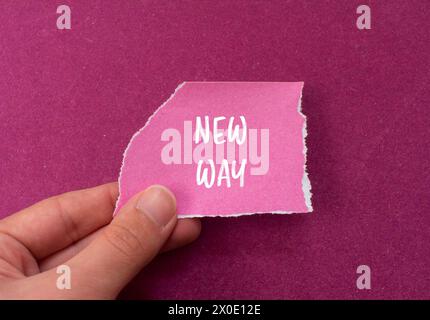 Mots de nouvelle façon écrits sur papier rose déchiré avec fond violet. Nouveau symbole conceptuel. Copier l'espace. Banque D'Images