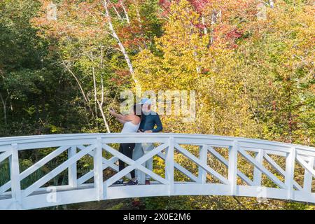 Touristes prenant un selfie sur le pont de Sommesville avec des couleurs d'automne en arrière-plan. Sommesville, Maine, États-Unis Banque D'Images