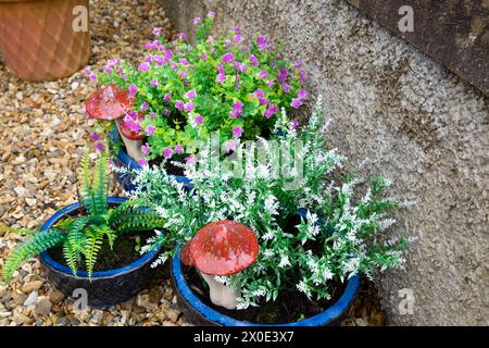 Kitsch plastique faux feuillage artificiel plantes feuillage et ornements de jardin champignon dans des pots bleus dans le jardin avant de la maison printemps pays de Galles UK KATHY DEWITT Banque D'Images