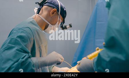 Docteur homme médecin chirurgien effectuer la chirurgie plastique liposuccion opération abdominale laparoscopique chirurgicale avec des instruments médicaux seringue dans l'infirmière Banque D'Images