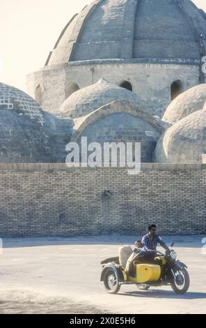 1988 archive photographie d'un homme et d'un garçon sur une moto avec side-car à l'extérieur du dôme commercial Toqi Zargaron - l'un des plus grands bazars de Boukhara, Ouzbékistan ; à cette époque une partie de l'URSS. Banque D'Images