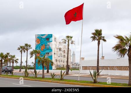 Casablanca, Maroc - 20 janvier 2019 : drapeau marocain agitant devant un bâtiment dans le quartier d'El Hank décoré d'une fresque de l'artiste de rue 'Sam Kirk'. Banque D'Images