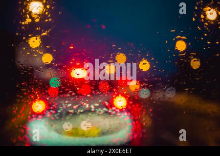 Vue à travers un pare-brise de voiture la nuit dans la circulation et la pluie battante Banque D'Images