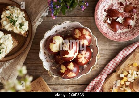 Œufs de Pâques bruns teints avec des pelures d'oignon, avec des tranches de pain au levain avec tartinade à base d'œufs durs sur une table en bois Banque D'Images
