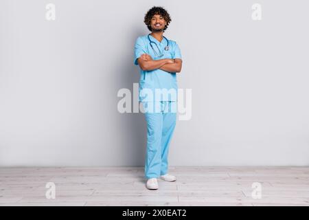 Photo du médecin professionnel Guy debout avec des mains croisées isolé fond de couleur grise Banque D'Images