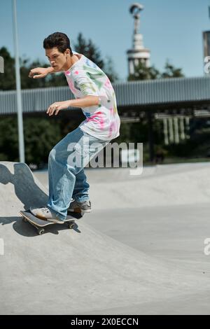 Un jeune patineur monte sans crainte son skateboard sur le côté d'une rampe dans un parc de skate extérieur animé par une journée d'été ensoleillée. Banque D'Images