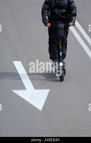 Vue d'un banlieue méconnaissable sur un scooter électrique entre les voies de la ville, illustrant l'intégration du transport compact et vert dans urba Banque D'Images