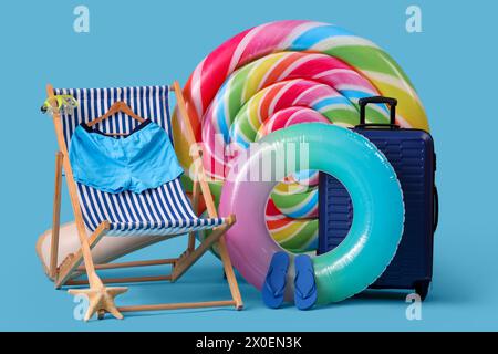 Matelas de natation en forme de bonbons, anneau gonflable et chaise longue avec des maillots de bain sur fond bleu Banque D'Images
