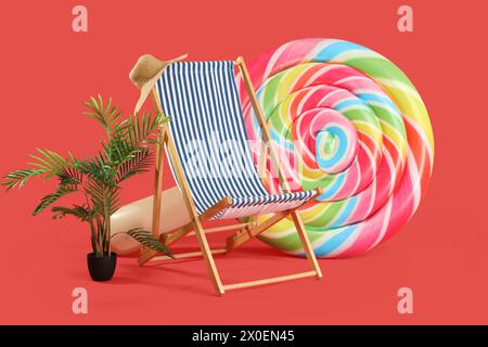 Chaise longue, plante et matelas gonflable en forme de bonbons sur fond rouge Banque D'Images