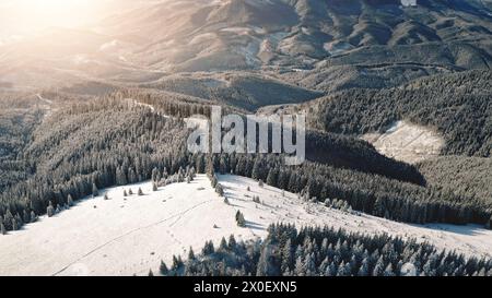 Lever de soleil aérien à la station de montagne de neige. Piste de ski solaire pour le sport actif touristique. Hiver personne nature paysage. Forêt d'épicéas au mont. Crête enneigée inconnue des Carpates, Bukovel Resort, Ukraine, Europe Banque D'Images