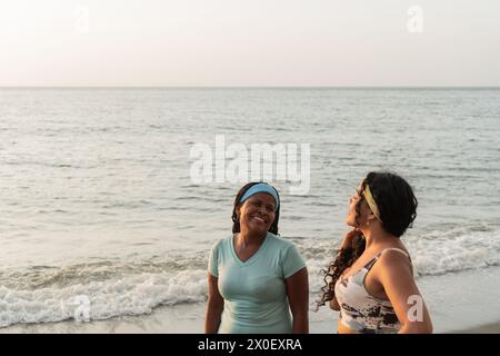 Deux femmes joyeuses partagent ensemble un moment joyeux sur fond de douces vagues de mer et un horizon clair. Banque D'Images