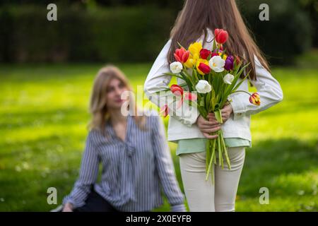 Fille cachant des tulipes derrière le dos. Banque D'Images