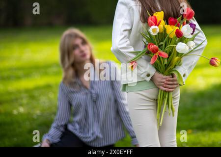 Fille cachant des tulipes derrière le dos. Banque D'Images