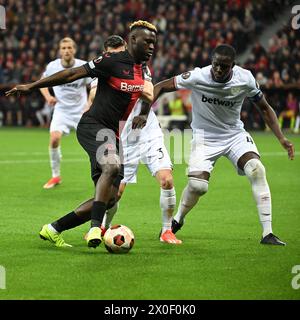 Leverkusen, Allemagne. 11 avril 2024. Victor Boniface (G) du Bayer 04 Leverkusen affronte Kurt Zouma du West Ham United FC lors du match des quarts de finale de l'UEFA Europa League entre le Bayer 04 Leverkusen et le West Ham United FC à Leverkusen, Allemagne, le 11 avril 2024. Crédit : Ulrich Hufnagel/Xinhua/Alamy Live News Banque D'Images