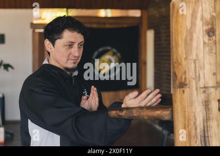 Homme pratiquant la formation traditionnelle de Wing Chun Kung Fu avec le mannequin en bois (Muk Yan Jong), un outil qui permet aux pratiquants de Kung Fu d'améliorer leur Banque D'Images