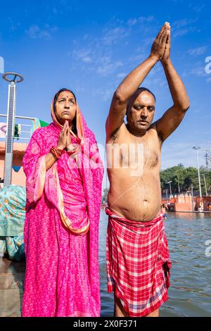 couple de dévots priant après la baignade dans l'eau de rivière sacrée le matin à partir d'un angle plat Banque D'Images