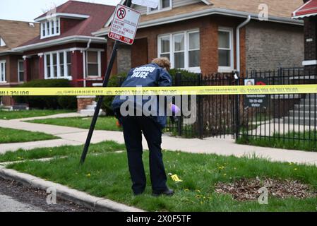 Un policier de Chicago prend des photos de douilles d'obus au sol, d'une arme à feu découverte au sol et d'un véhicule frappé par des coups de feu sur la scène du crime. Homme de 20 ans abattu par une autre personne et placé en détention par la police à Chicago, Illinois, États-Unis le 11 avril 2024. Jeudi après-midi vers 14h17, dans le bloc 1500 de l’avenue N. Leclaire, un homme de 20 ans a été découvert pour avoir subi une blessure par balle à la jambe droite après avoir été impliqué dans un échange de coups de feu avec un inconnu. La victime a été transportée à l'hôpital en bon état Banque D'Images