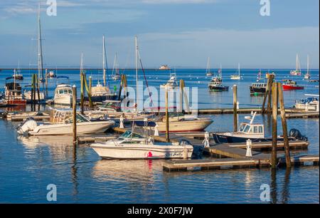 Bateaux amarrés à Landings Marina à Rockland Harbor, Maine, États-Unis, avec un phare visible en arrière-plan par temps clair. Banque D'Images