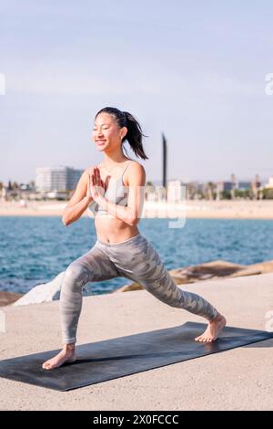 femme en sportswear pratiquant le yoga au bord de la mer Banque D'Images