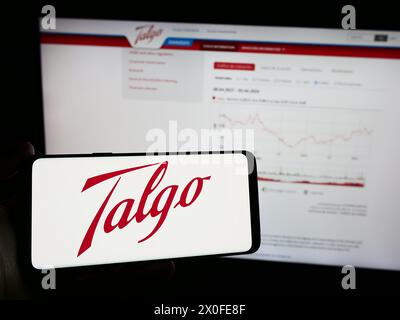 Personne tenant le téléphone portable avec le logo de la société espagnole de fabrication de train Talgo sa en face de la page Web de l'entreprise. Concentrez-vous sur l'affichage du téléphone. Banque D'Images