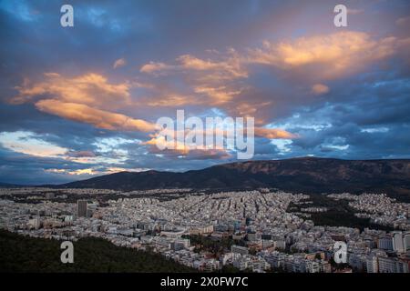 Coucher de soleil majestueux avec de merveilleux nuages sur le mont Hymettus et la ville d'Athènes, Grèce. Il y a plusieurs districts inclus comme Zografou et Papagou. Banque D'Images