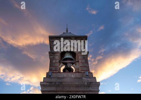 Beffroi en pierre avec cloche en bronze au sommet du mont Lycabette, Athènes, lors d'un coucher de soleil glorieux avec des nuages colorés. Banque D'Images