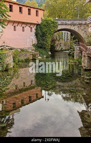 Belle rivière de la ville avec pont de pierre, à la vieille ville de Livadeia, la ville principale de la région de Boeotia, en Grèce centrale, Europe. Banque D'Images