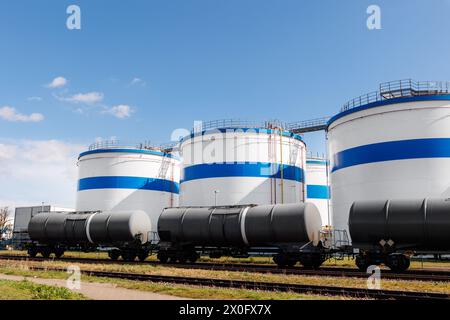 Rangée de nombreux grands réservoirs blancs de stockage de carburant industriel fond bleu clair de ciel le jour ensoleillé. Installations de dépôt de liquides de raffinerie de stockage de pétrole. Produit dangereux pour l'énergie Banque D'Images