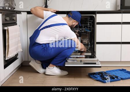 Réparateur lave-vaisselle dans la cuisine, vue arrière Banque D'Images