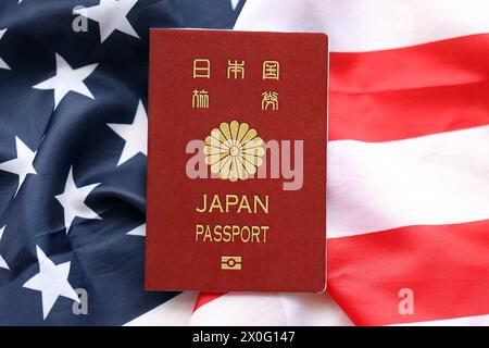 Passeport japonais sur fond de drapeau national des États-Unis gros plan. Tourisme et concept de diplomatie Banque D'Images