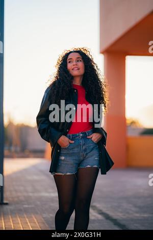 Femme aux cheveux bouclés en chemise rouge et veste noire Banque D'Images