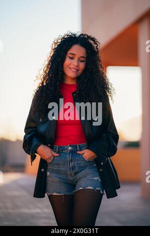 Femme aux cheveux bouclés en chemise rouge et veste noire Banque D'Images