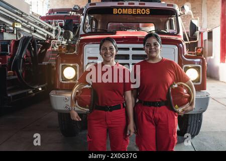 Portrait de pompiers femmes heureuses debout contre un moteur de pompier Banque D'Images