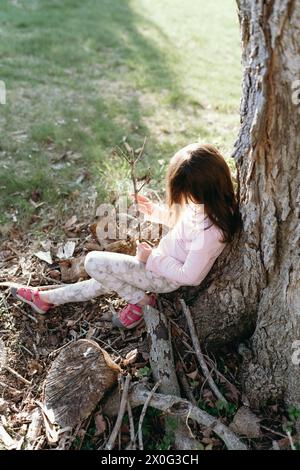 petite fille assise sous un arbre profitant de la nature Banque D'Images