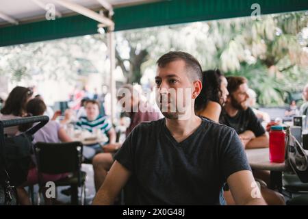 L'homme est assis seul dans un café en plein air animé à la Nouvelle-Orléans en juillet 2017 Banque D'Images