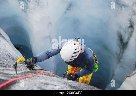 Homme glace grimpant une crevasse de glacier sur un glacier islandais Banque D'Images