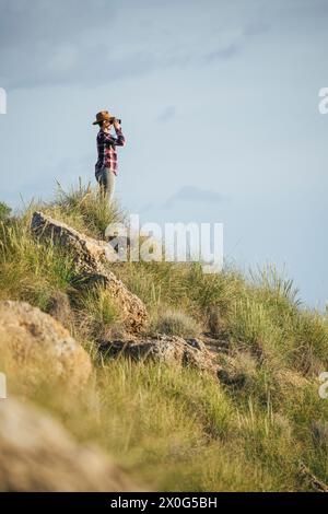 Femme avec chapeau et tenue à carreaux regardant le désert. Banque D'Images