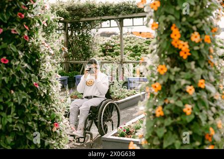 Adolescente en fauteuil roulant prenant des photos dans le jardin Banque D'Images