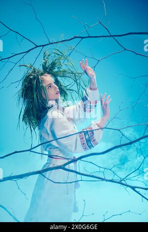 Un jeune mavka en tenue traditionnelle avec des dreadlocks ornés debout gracieusement devant un arbre majestueux. Banque D'Images