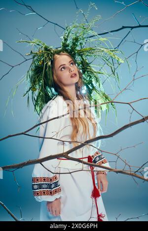 Une jeune mavka se tient gracieusement devant un arbre, vêtue d'une tenue traditionnelle avec une couronne ornée sur la tête. Banque D'Images