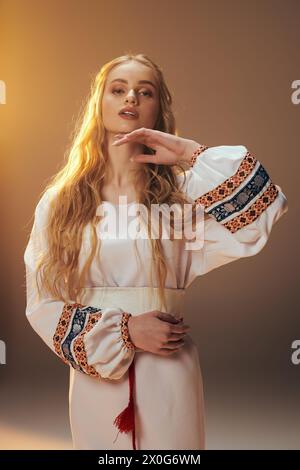 Une jeune fille vêtue de blanc pose gracieusement, incarnant une aura de fée et de fantaisie dans un cadre de studio. Banque D'Images