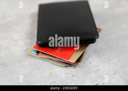 Beaucoup de cartes de crédit différentes et portefeuille en cuir sur la table grise, gros plan Banque D'Images